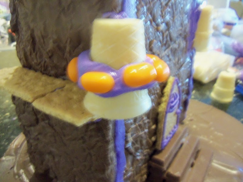 Cut 2 cake cones to fit the front corners. Decorate them with icing and Jelly Belly candies