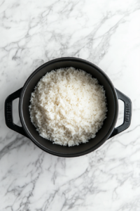 This image shows jasmine rice simmering in chicken stock with the pot covered, allowing the rice to absorb all the flavors while cooking to a tender texture.