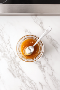 This image shows warm water being mixed with honey in a mason jar, creating the base for the apple cider vinegar shots, ensuring the honey dissolves smoothly.