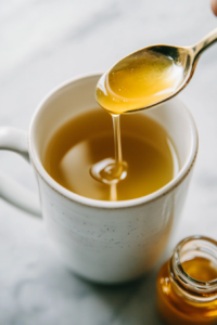 This image shows a spoonful of honey being stirred into the cortisol cocktail mixture, offering a touch of natural sweetness to the drink.