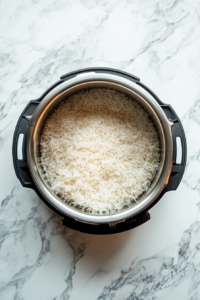 This image shows the rinsed Calrose rice being added to the Instant Pot along with cold water, getting ready for pressure cooking.