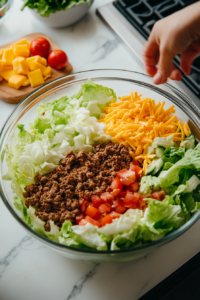 This image shows freshly chopped iceberg lettuce and diced tomatoes being prepared as the base of the Frito Taco Salad, providing a crisp and refreshing contrast to the seasoned meat.