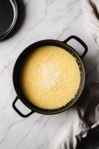 This image shows the finished Gouda Grits, perfectly creamy and smooth, being ladled into a serving bowl, ready to enjoy.