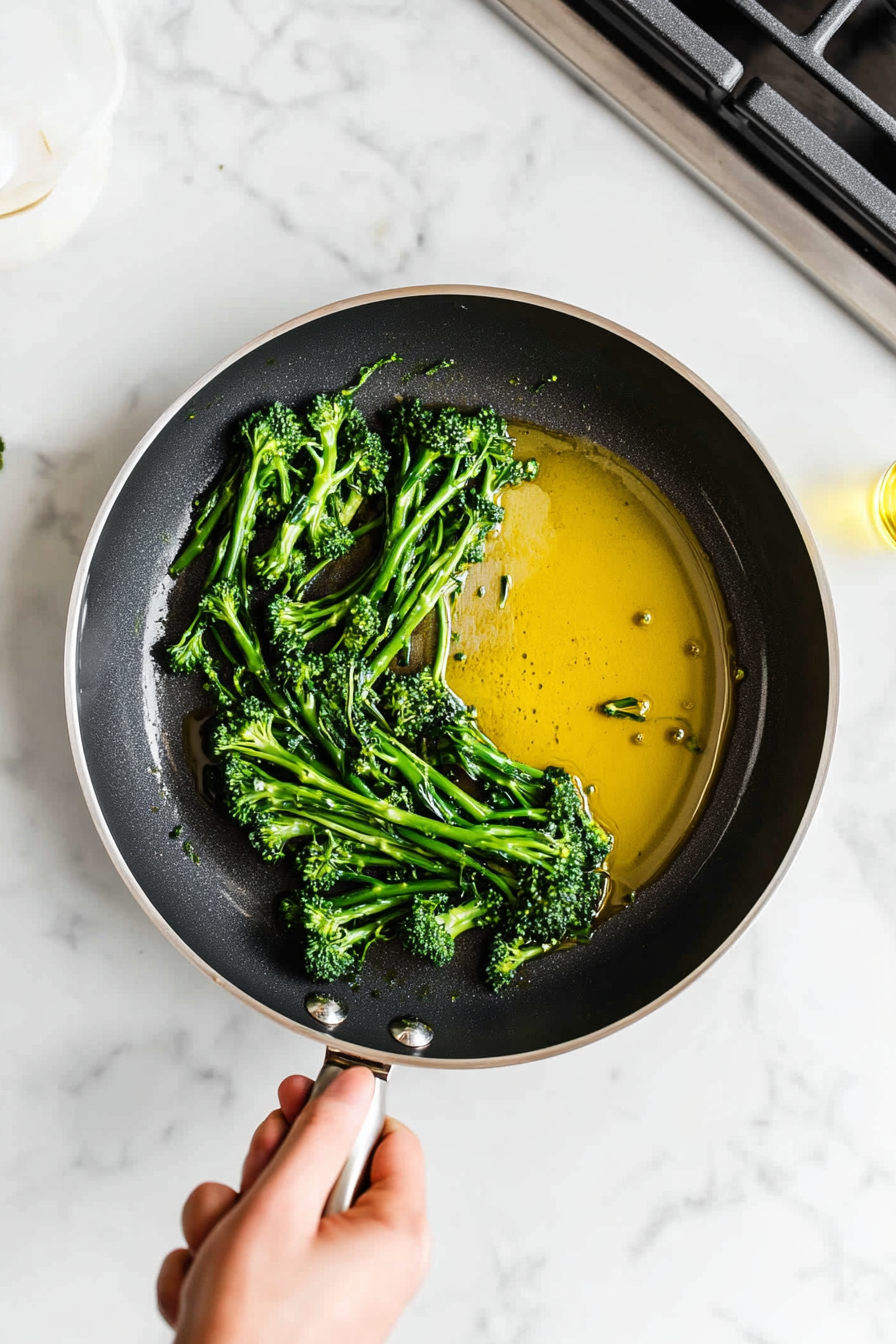 This image shows a skillet being heated on medium heat with olive oil gently swirling in the pan, ready to cook the broccolini to crispy perfection.