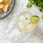 This image shows a refreshing margarita served in a chilled glass, featuring a salted rim and garnished with a lime wedge, showcasing the perfect balance of tequila, lime, and sweetness.