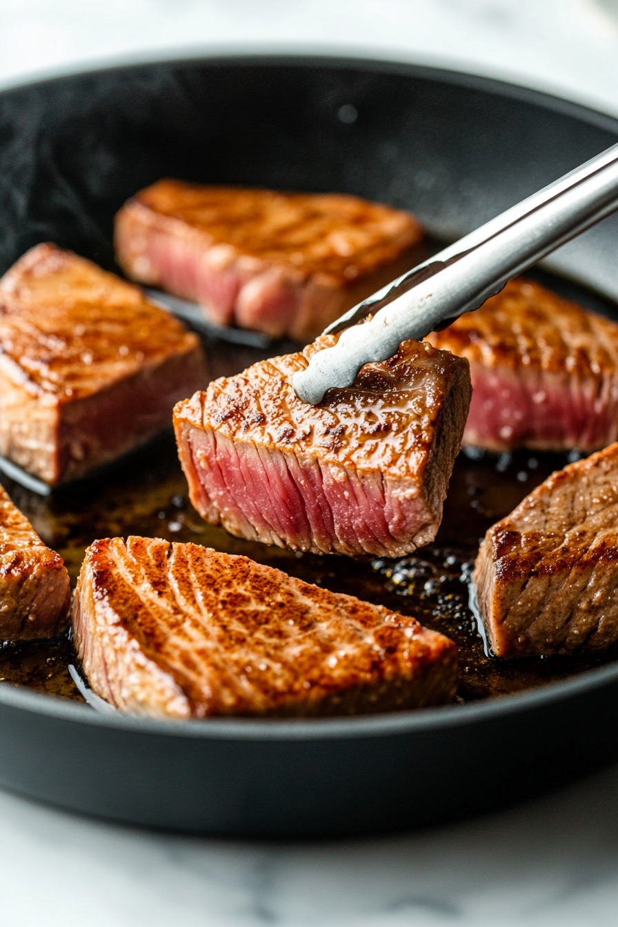 This image shows yellowfin tuna steaks being seared in a skillet, forming a golden brown crust on the outside while keeping the center pink and tender.