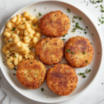 This image shows a plate of perfectly cooked Southern salmon patties, garnished with fresh herbs, served alongside mac and cheese and other classic Southern sides, ready to be enjoyed.