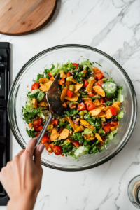 This image shows all the ingredients for the Frito Taco Salad being tossed together, including the seasoned beef, crunchy corn chips, fresh vegetables, and Catalina dressing for a flavorful, hearty salad.