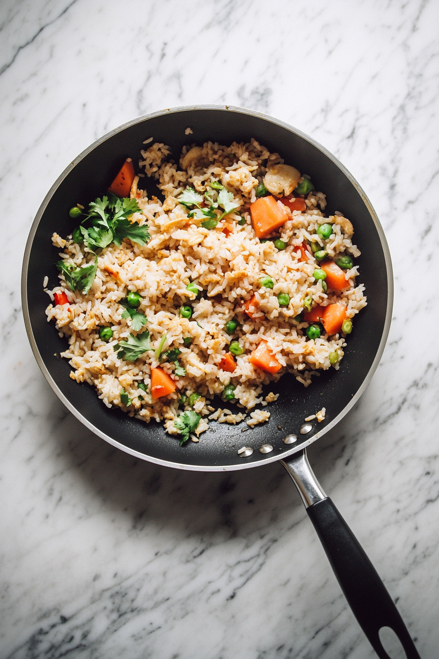 This image shows sesame oil being stirred into the kimchi fried rice, adding a nutty aroma, with the rice being thoroughly mixed and ready to be plated.