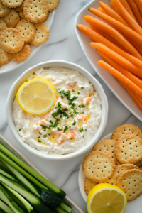 This image showcases the chilled Cold Crab Dip served in an elegant dish, surrounded by an assortment of crackers and crisp fresh vegetables, making it a perfect appetizer for gatherings.