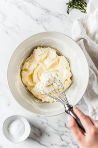 This image shows softened butter and sugar being creamed in a mixing bowl, creating a smooth and fluffy base for the pickle cake.