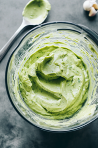 This image shows the blender in action, blending together the avocados, garlic, sour cream, lime juice, and cilantro to create a smooth and flavorful avocado crema.