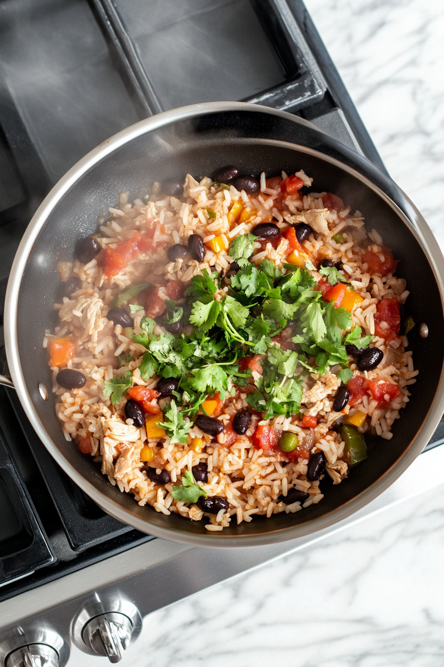 This image shows the mixture of chicken broth, salsa, black beans, and seasonings bubbling gently in the skillet, covered to simmer for 25 minutes until the rice is perfectly cooked and infused with flavors.