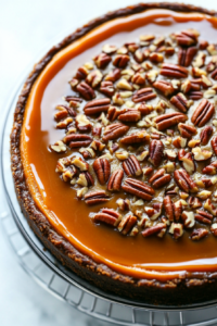 This image shows the hot pecan topping being poured over the baked sweet potato cheesecake, adding a rich and crunchy layer to the dessert.