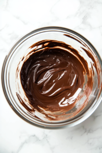 This image shows Nutella being mixed into the smooth, melted chocolate and butter mixture, enhancing the rich, nutty flavor of the brownie batter.