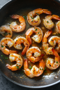 This image shows shrimp being sautéed in a skillet. The shrimp are cooked until they turn pink and opaque, ensuring they are tender and flavorful.