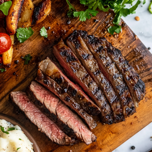 This image shows that a perfectly smoked ribeye steak, with a rich, smoky crust and a juicy interior, is ready to be served. The steak is presented with garnishes and sides, highlighting its tender and flavorful qualities.