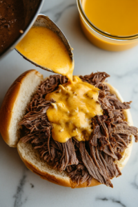 This image shows the beef and cheddar sandwiches being assembled by placing warm roast beef on onion buns and generously topping with smooth, melted cheddar cheese.