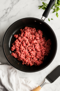 This image shows ground beef pressed into the bottom of the pot as it browns, forming a large patty for Wendy’s chili. The beef is starting to develop a rich brown color.