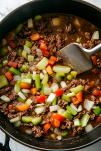 This image shows chopped onions, celery, and green bell peppers cooking in the pot, turning soft and translucent to add flavor to Wendy’s chili.