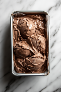 This image shows the loaf tin filled with Nutella ice cream covered with cling wrap and placed into the freezer for 7-8 hours or overnight to set.