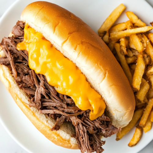 This image shows a close-up of a homemade beef and cheddar sandwich, featuring tender slices of roast beef and creamy melted cheese on a fresh onion bun, served with curly fries for a delicious fast-food experience at home.