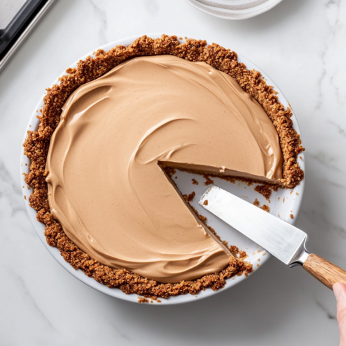 This image features the finished no-bake peanut butter pie with a smooth peanut butter filling and a golden graham cracker crust, ready for serving.