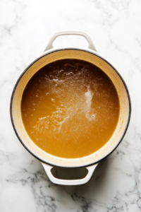 This image shows beer being poured into the pot over the roux, creating the base for the beer cheese soup and adding depth of flavor.