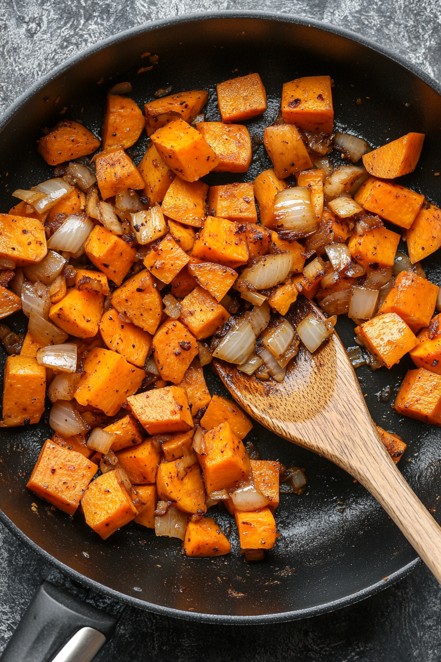 This image shows onion wedges and crushed garlic being sautéed in a saucepan until softened, preparing the fragrant base for the Thai red curry vegetables.