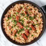 This image shows the Smoked Sausage and Rice dish, featuring savory smoked sausage, tender bell peppers, and rice infused with rich tomato flavors. The dish is beautifully presented in a skillet, garnished with fresh parsley for an inviting and hearty meal.