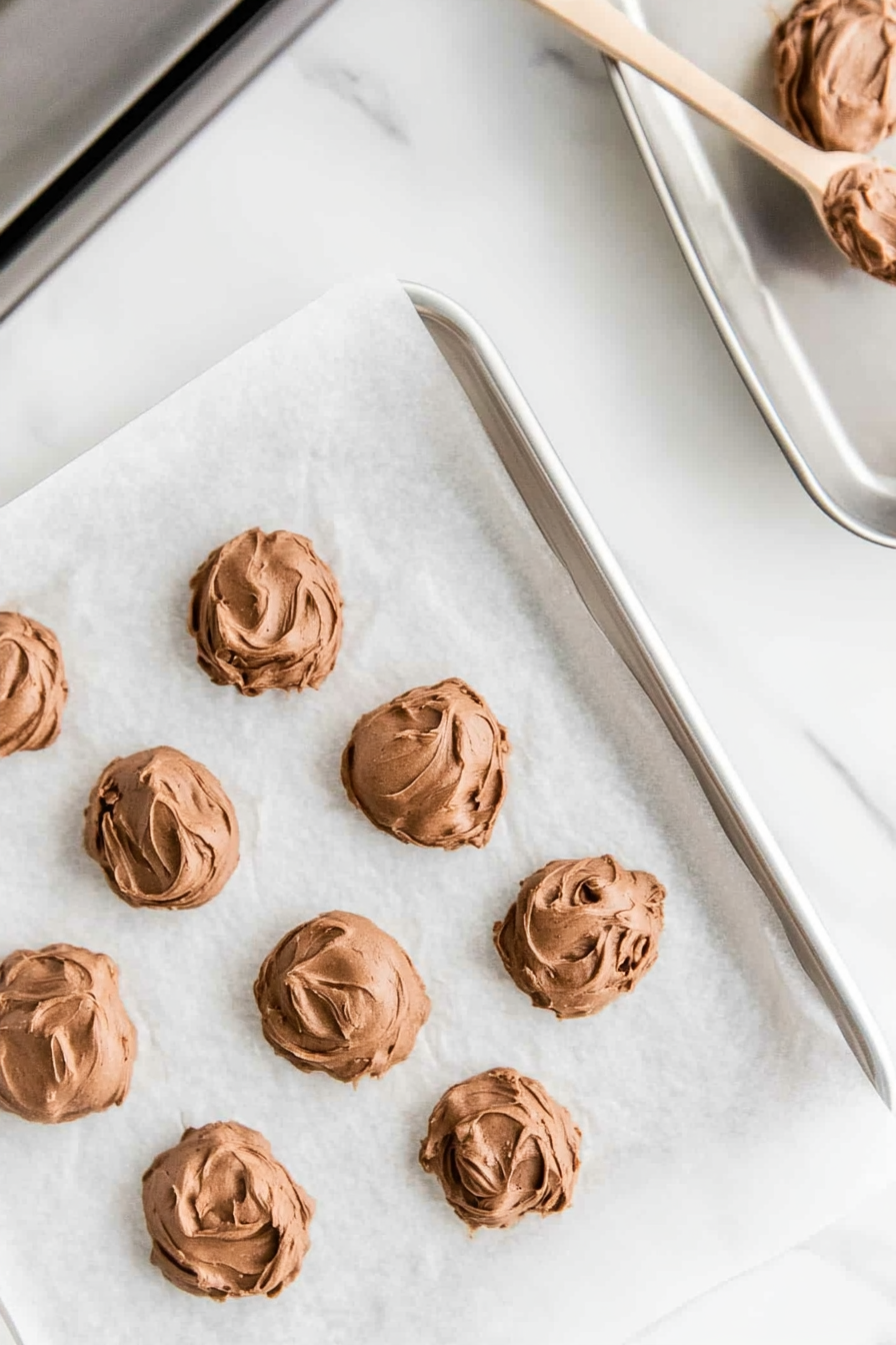 This image shows spoonfuls of Nutella cookie dough being scooped onto the prepared baking sheets, spaced 2 inches apart to ensure even baking.