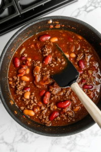 This image shows the chili simmering gently in the pot, with bubbles rising as the flavors deepen over time for Wendy’s chili.