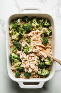 This image shows shredded chicken being added to the dish, followed by cheese, with each ingredient being mixed thoroughly.