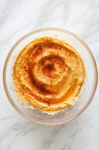 This image shows the pumpkin dip arranged in the center of a serving platter, surrounded by cookies, mini desserts, and fresh fruits, ready for dipping.