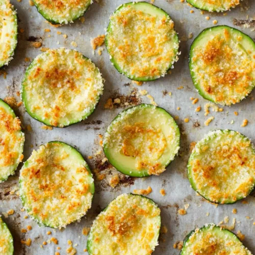 Top-down view of golden, crispy avocado parmesan chips cooling on the baking sheets after baking, ready to be served.