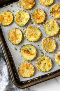 Top-down view of golden, crispy avocado parmesan chips cooling on the baking sheets after baking, ready to be served.