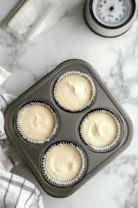 This image shows flour and baking powder being gradually folded into the wet ingredients, forming the final cupcake batter.