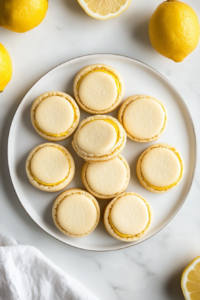 This image shows a serving plate with lemon sandwich cookies neatly arranged in a circle. The cookies are garnished with thin slices of fresh lemon and sprigs of mint for a pop of color. The creamy lemon filling is visible between the golden cookies, inviting guests to indulge in a zesty, refreshing treat.