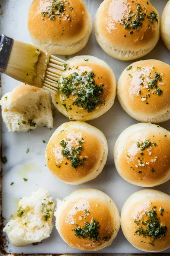 This image shows the tops of the slider buns being brushed with the prepared garlic butter before baking.