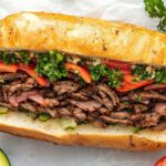 Top-down view of the chopped sandwich mixture being spooned onto a hoagie roll. The scene focuses on the hoagie roll stuffed with the flavorful, well-mixed Italian sub ingredients, ready to be served.