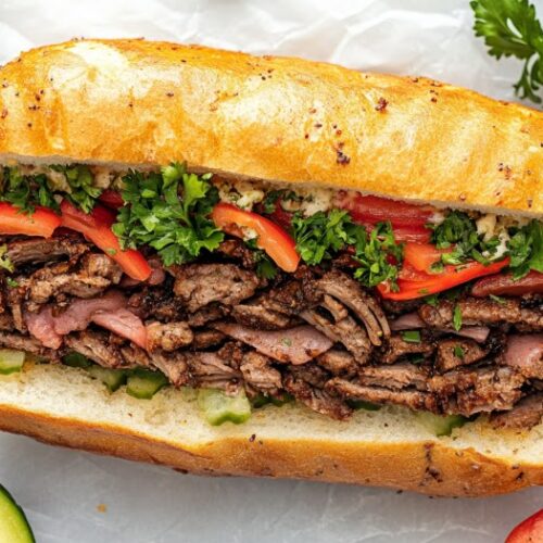 Top-down view of the chopped sandwich mixture being spooned onto a hoagie roll. The scene focuses on the hoagie roll stuffed with the flavorful, well-mixed Italian sub ingredients, ready to be served.