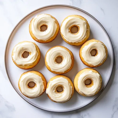 This image shows a plate of golden-brown Cinnabon Delights, each filled with cream cheese glaze, dusted in cinnamon sugar, and arranged in a tempting pile.