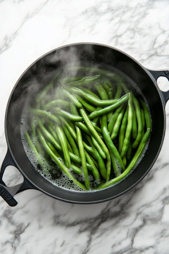 This image shows green beans being cooked until tender but still firm enough to be easily pierced with a fork, ensuring they remain slightly undercooked for further cooking later.