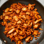 Top-down view of cooked jackfruit in the pan, being tasted and adjusted with additional salt, spices, cayenne pepper, or lime juice, ready to be served in tacos, burritos, enchiladas, or bowls.