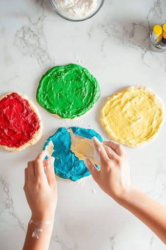 This image shows the colorful dough being rolled out to 7-8mm thickness and dinosaur shapes being cut out with a cookie cutter.