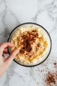 This image shows the smooth pumpkin dip transferred to a serving dish, with cinnamon sprinkled on top as a garnish.