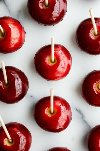 This image shows the freshly coated candy apples placed on the greased cookie sheet, hardening as the candy shell sets.