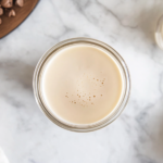 Top-down view of a sealed airtight container or glass bottle filled with homemade Irish cream, placed on a white marble cooktop. The Irish cream is ready to be stored in the refrigerator for up to 2 months.