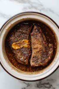 This image shows a small bowl with brown sugar, paprika, garlic powder, onion powder, salt, and pepper being combined to create a spice rub for seasoning the beef.