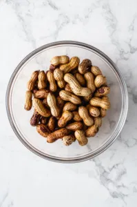 Top-down view of drained boiled peanuts served in a large bowl, ready to eat.